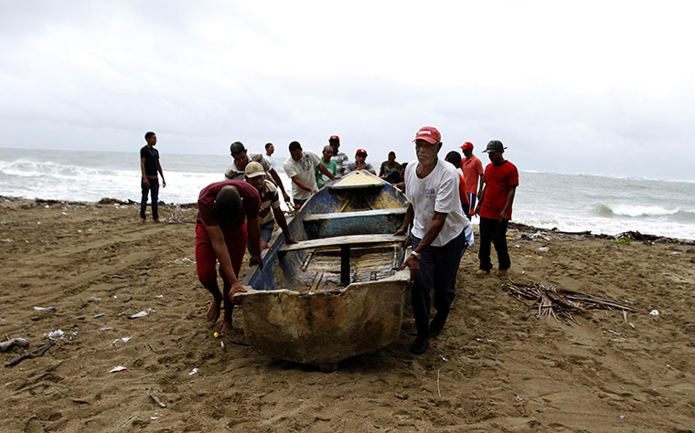 Hurricane Irene: Men take a boat out of the sea on a beach in Santo Domingo