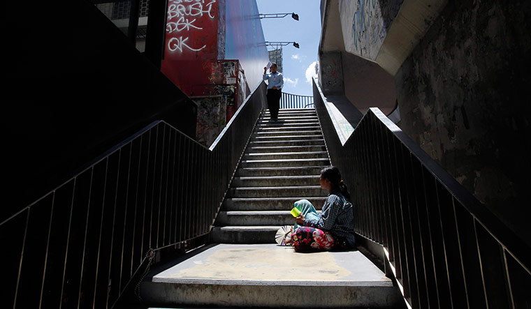 24 hours in pictures: A homeless woman begs on a foot bridge in Bangkok