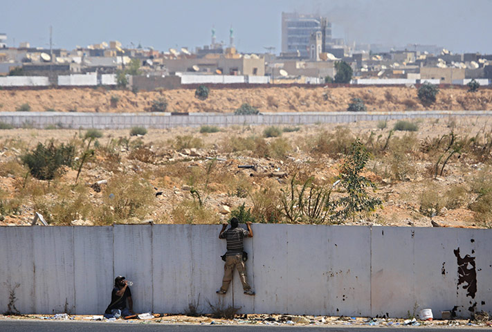 Battle for Tripoli: Rebel fighters observe the fighting near the main Muammar Gaddafi compound