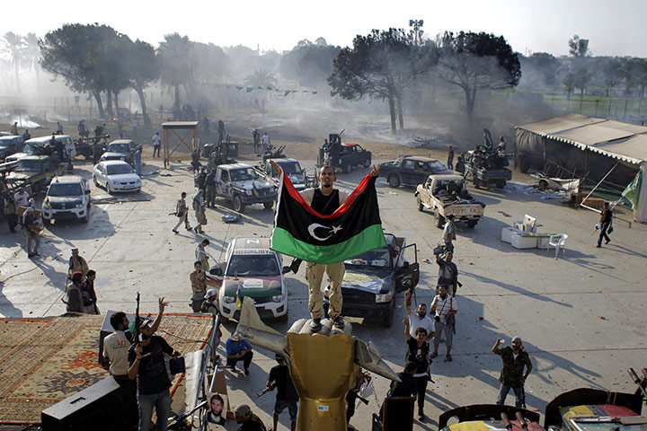 Gaddafi's compound falls: A rebel fighter gestrures as he stands on the monument inside the compound