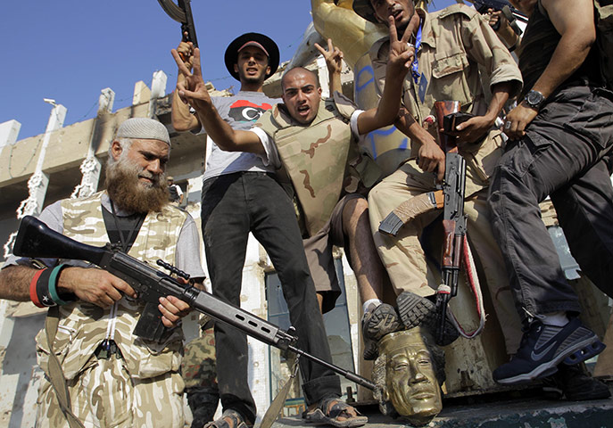 Gaddafi's compound falls: Rebel fighters stamp on the head of a Gaddafi statue inside his compound 