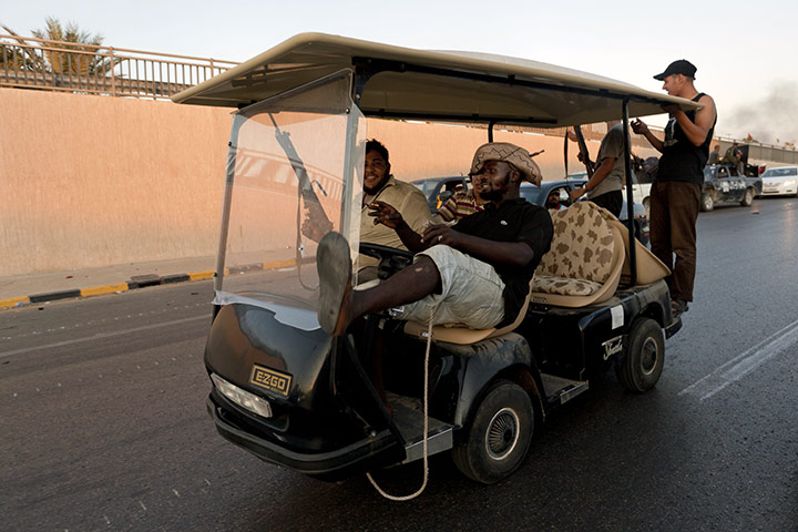 Gaddafi's compound falls: Rebel fighters ride in a golf buggy taken from Gaddafi's headquarters