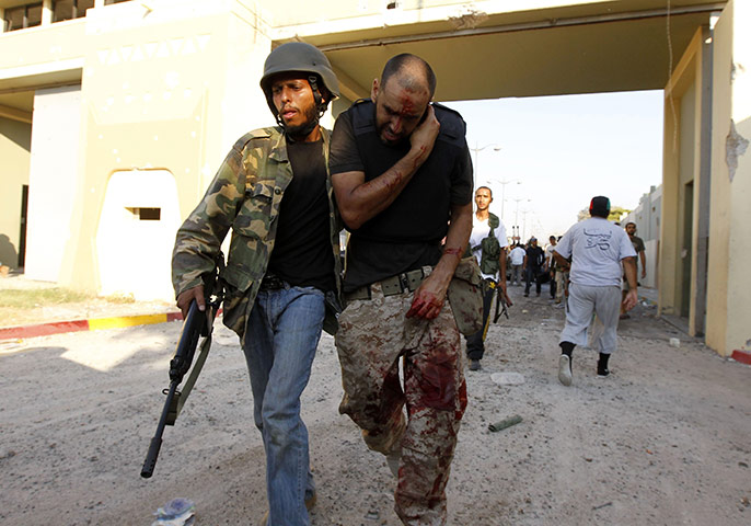 Gaddafi's compound falls: A Libyan rebel assists an injured fellow rebel 