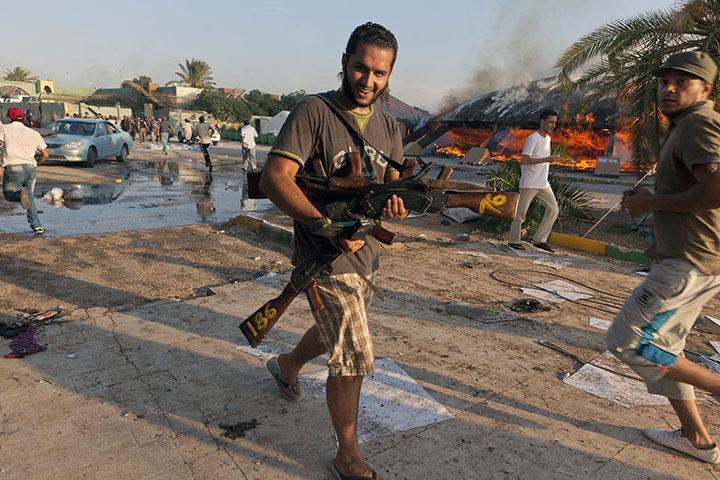 Gaddafi's compound falls: A rebel carries guns he's taken