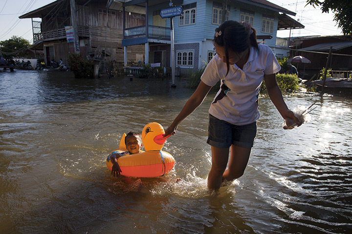 24 hours: Phinchit, Thailand: A boy gets a ride in a rubber duck in floods