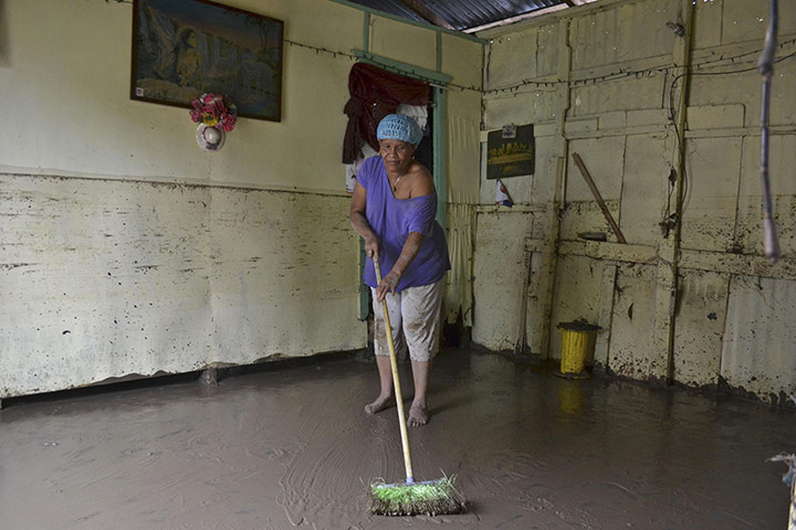 Hurricane Irene: A woman sweeps the mud off the living room of her house in San Cristobal