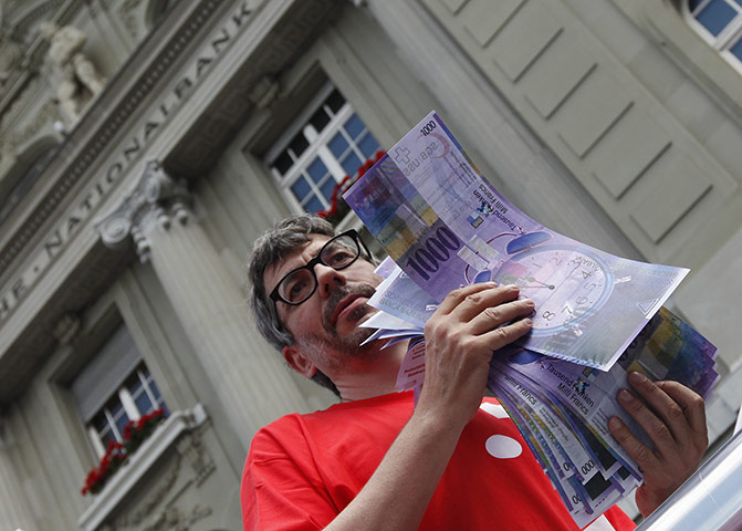 Week in Business: A trade union member holds up mock Swiss franc banknotes during a protest 