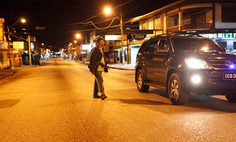 A policeman approaches a vehicle for questioning after curfew hours in Trinidad and Tobago.  (Image Courtesy of The Guardian)