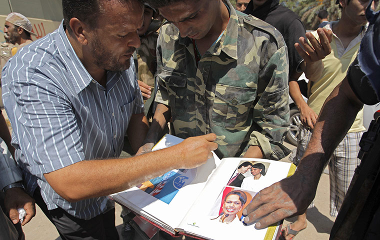 Raids in Tripoli: Rebel fighters look through an album including pictures of Condoleezza Rice