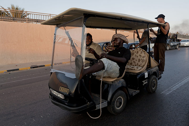 Raids in Tripoli: Fighters ride in a golf buggy taken from Gaddafi's headquarters