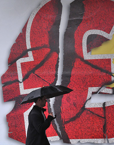 Week in Business: A man passes an advertising poster featuring a crumbling British pound sign
