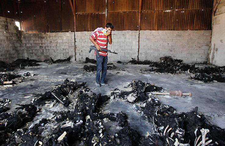 24 hours in pictures: A rebel fighter looks at the charred remains of burnt bodies, Tripoli