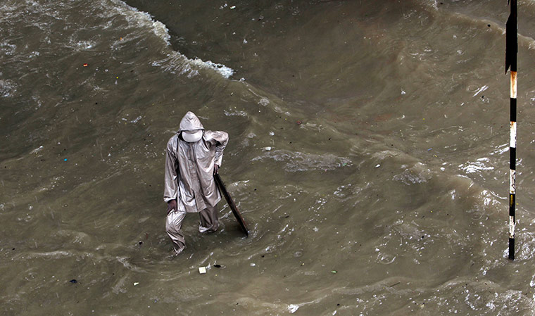 24 hours in pictures: A man stands on a water-logged street during heavy rains in Mumbai