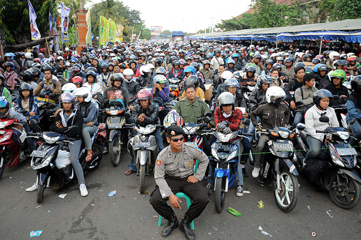 24 hours in pictures: A policeman sits at the access as motorists wait to board a ferry, Bali