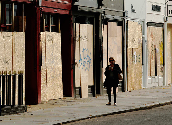 Notting Hill carnival: A woman passes boarded up shops ahead of the annual Notting Hill Carnival