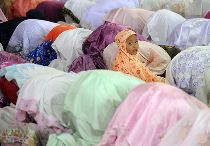 24 Hours : Jakarta, Indonesia: A young girl looks on as Indonesian women pray