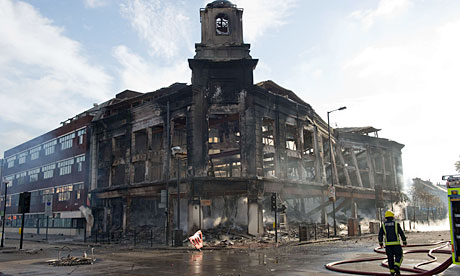 In Tottenham, firefighters survey the burnt out shell of a carpet showroom on Tottenham High Road