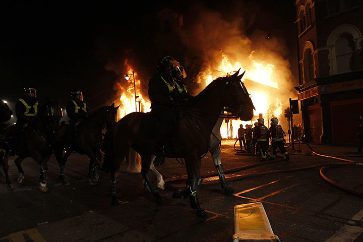Tottenham riots: Mounted police ride in front of a burning building 