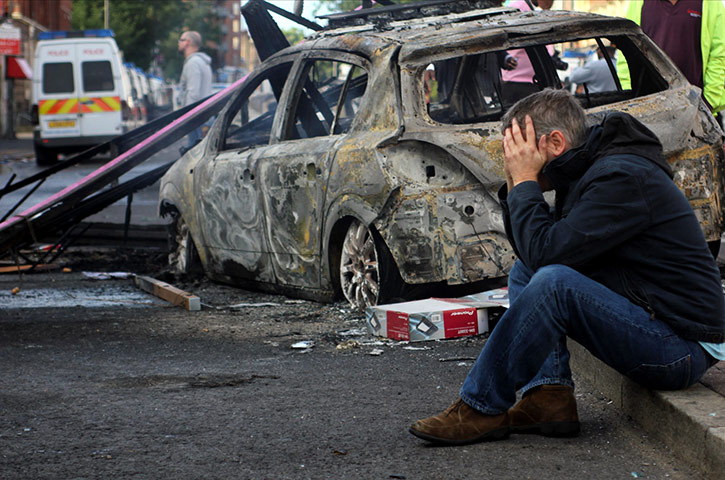 Tottenham riots: A local resident next to a burnt car 
