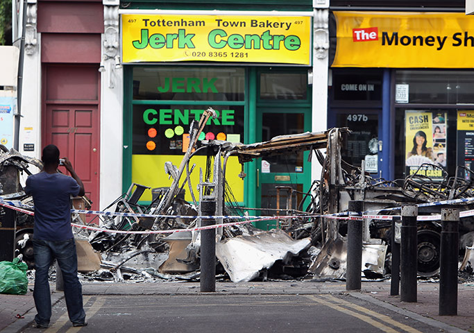 Tottenham riots: A man photographs a burnt out bus on Tottenham High Road 