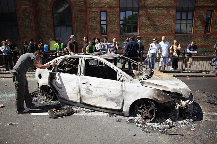 Tottenham riots: A man photographs a burnt out police car