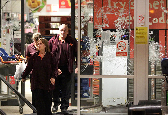 London riots: Staff leave a damaged Sainsbury's sstore in Enfield 