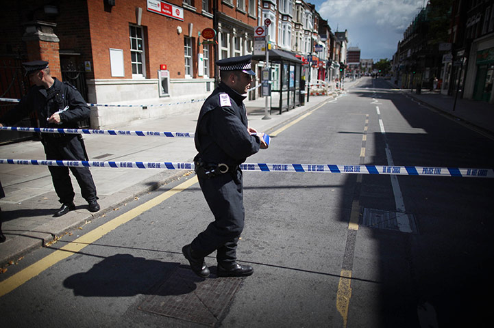 London Riots: A policeman puts tape across Church Street in Enfield 