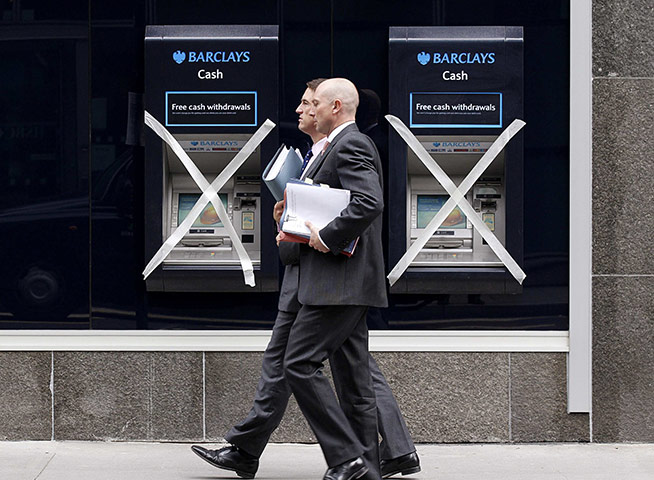 Week in Business: Two men pass a pair of closed ATMs with masking tape in City of London