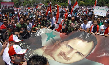 Syrians carry a flag bearing a picture of President Bashar Assad