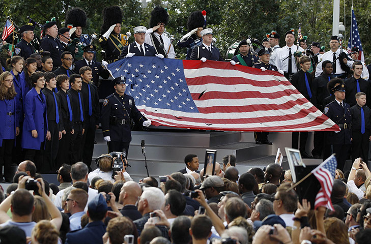 9/11 anniversary: New York City firefighters and police officers hold a damaged flag