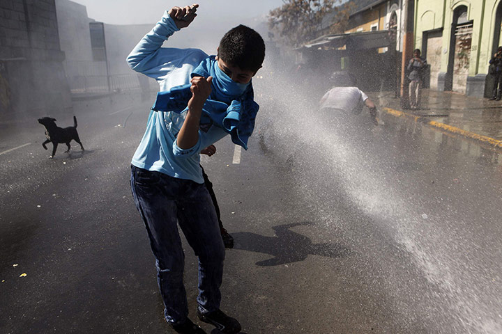 24 hours: Santiago, Chile: A demonstrator is hit by a jet of water during a protest