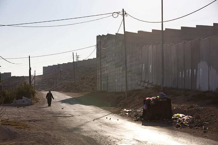 Al-Walaja: a woman walks past the wall