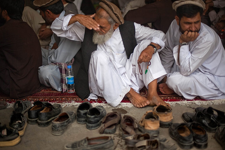 24 hours in pictures: illage elder looks for his shoes during a jirga hosted by the US army
