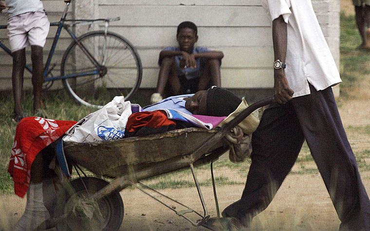 Robert Mugabe: November 2008: A man pushes his relative in a barrow to a cholera clinic