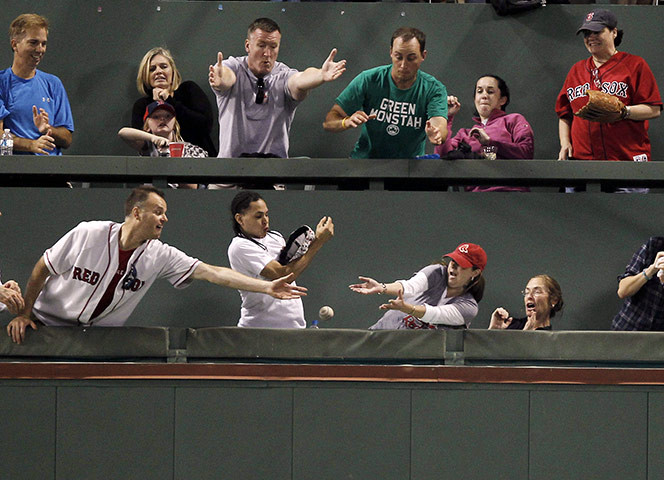 24 hours in pictures: Boston, US: Fans in the Green Monster seats reach for the ball