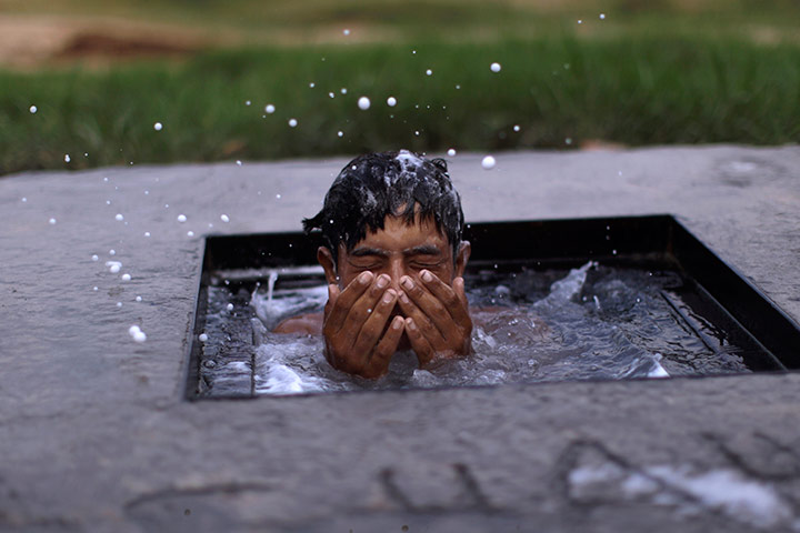 24 hours in pictures: Pakistani youth washes in a water 