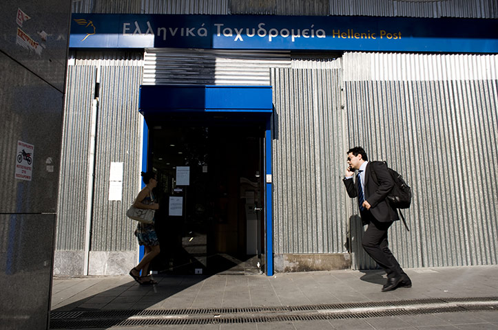 24 hours in pictures: A man walks past the boarded-up exterior of Post Office in Syntagma square