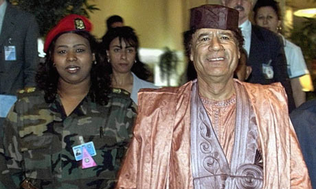 Muammar Gaddafi flanked by a member of his female-only bodyguards