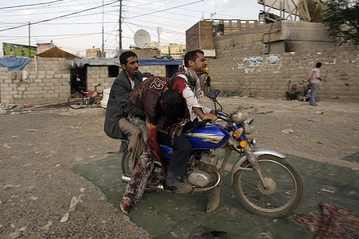 Yemen violence: Anti-government protesters use a motorcycle to evacuate a wounded cameraman