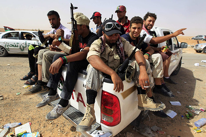 Libya fighting continues: Anti-Gaddafi fighters sit at a checkpoint after retreating from Bani Walid