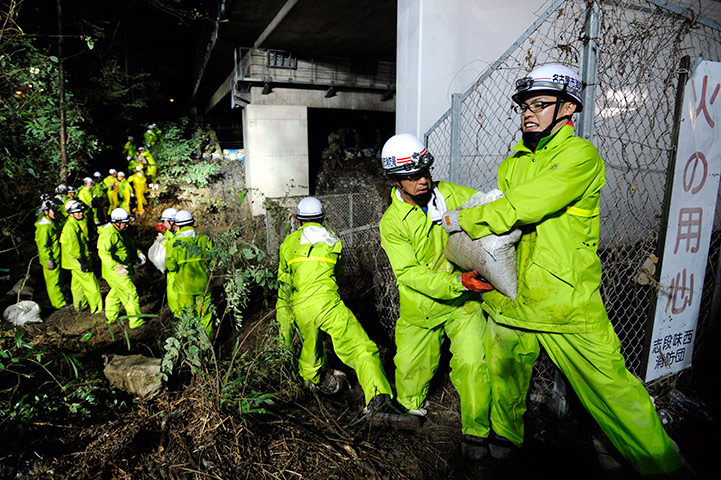 Typhoon Roke: Rescue team members prepare sandbags to secure a river bank
