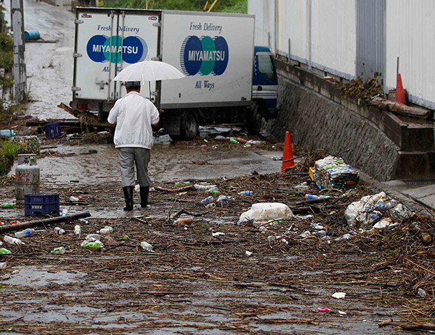 Typhoon Roke: A man walks toward a damaged truck at a factory close to the Shonai river