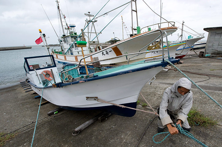 Typhoon Roke: A Japanese fisherman ties down his fishing boat