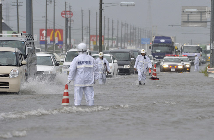 Typhoon Roke: police officers in rain gear regulate vehicles on a flooded national route