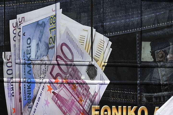Week in Business: A  man sits in a bus featuring an advertisement of the lottery in Athens 