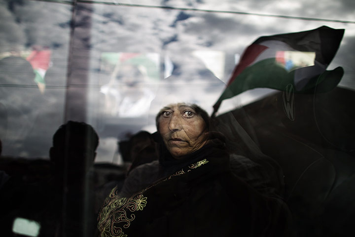 24 hours in pictures: Qusra, West Bank: A Palestinian woman looks towards mourners