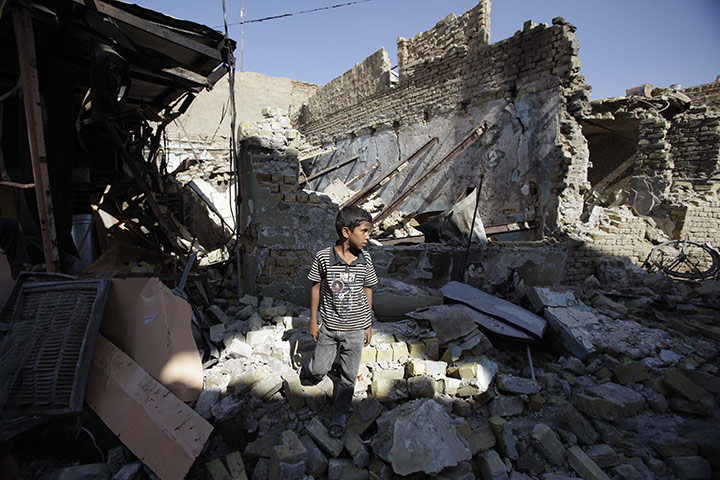 24 hours: Karbala, Iraq: An Iraqi boy stands in front of his destroyed home 