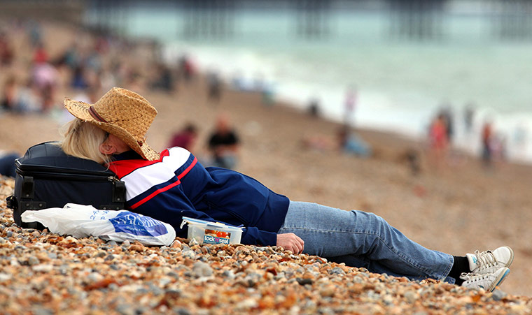 Hot Weather in the UK: A sunbather enjoys the beach in Brighton, East Sussex