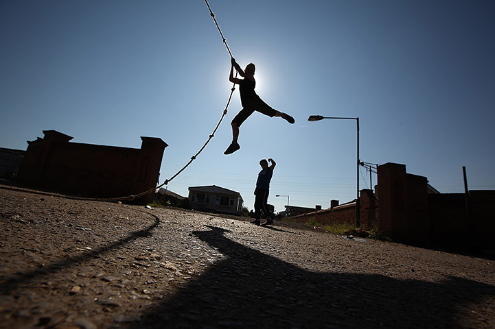 24 hours in pictures: Basildon, UK: A youth plays on a rope at Dale Farm travellers camp