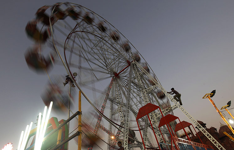 24 hours in pictures: New Delhi, India: A worker ascends a ladder to a giant wheel